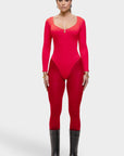 Woman wearing a red bodysuit with long sleeves and black boots on a white background