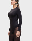 Woman wearing a black bodysuit with sheer panels on a white background