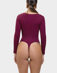 Person wearing a burgundy long-sleeve bodysuit on a white background
