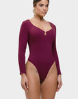 Woman wearing a burgundy long-sleeve swimsuit on a white background