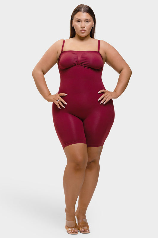 Woman wearing a maroon bodysuit against a white background