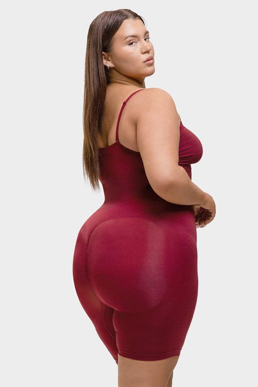 Woman wearing a maroon bodysuit against a white background