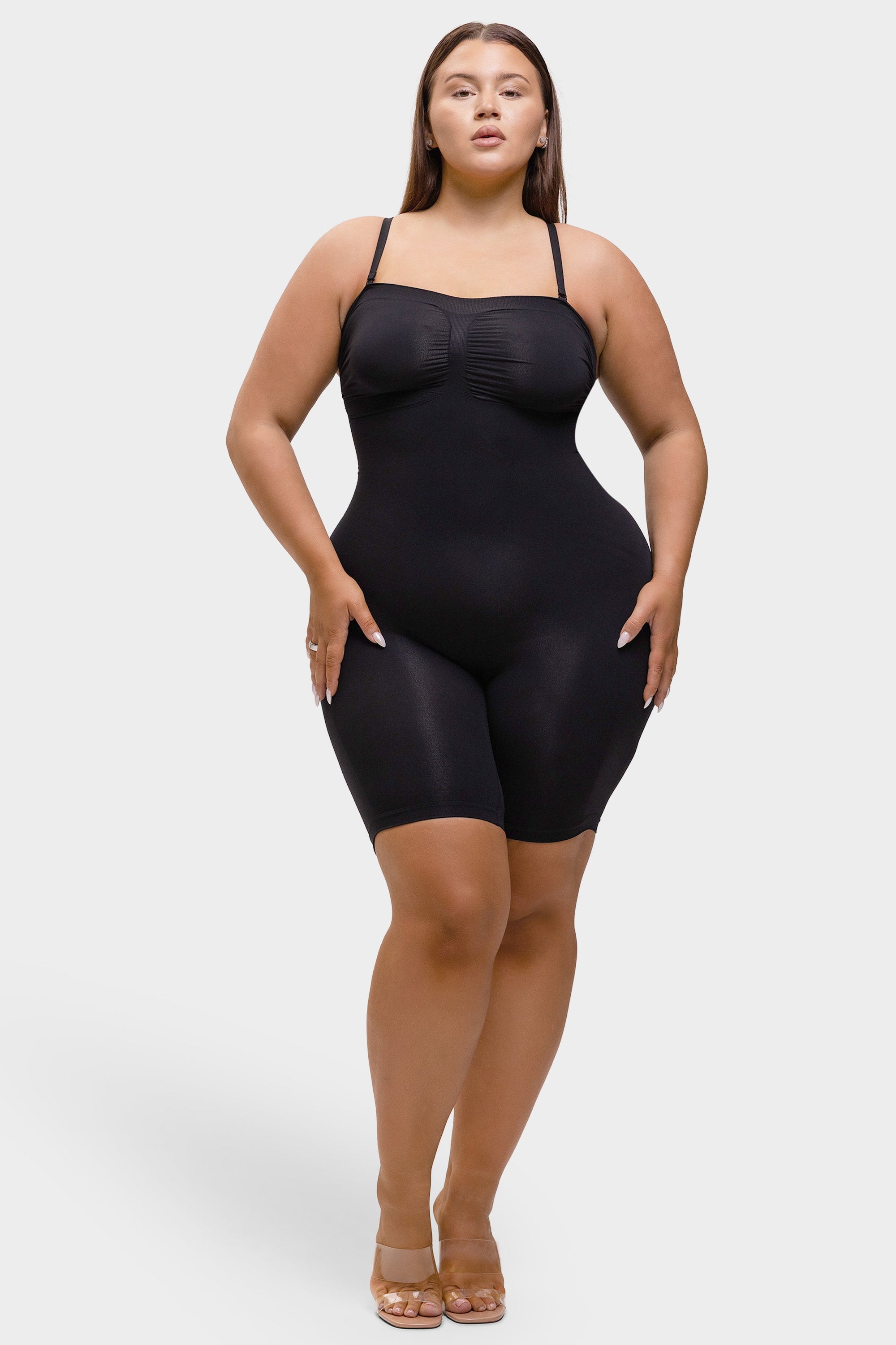 Woman wearing a black shapewear bodysuit on a white background