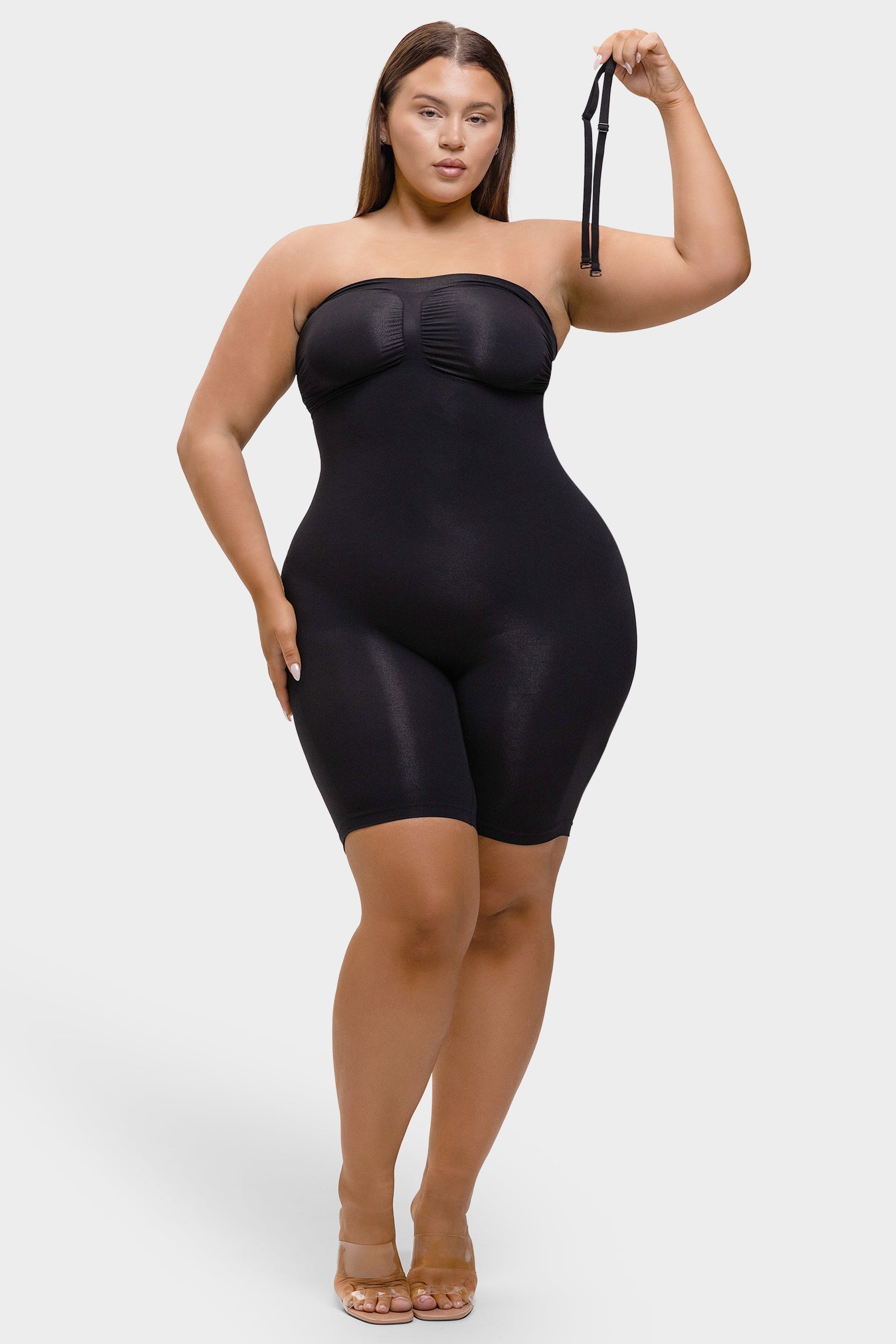 Woman wearing a black strapless bodysuit against a white background