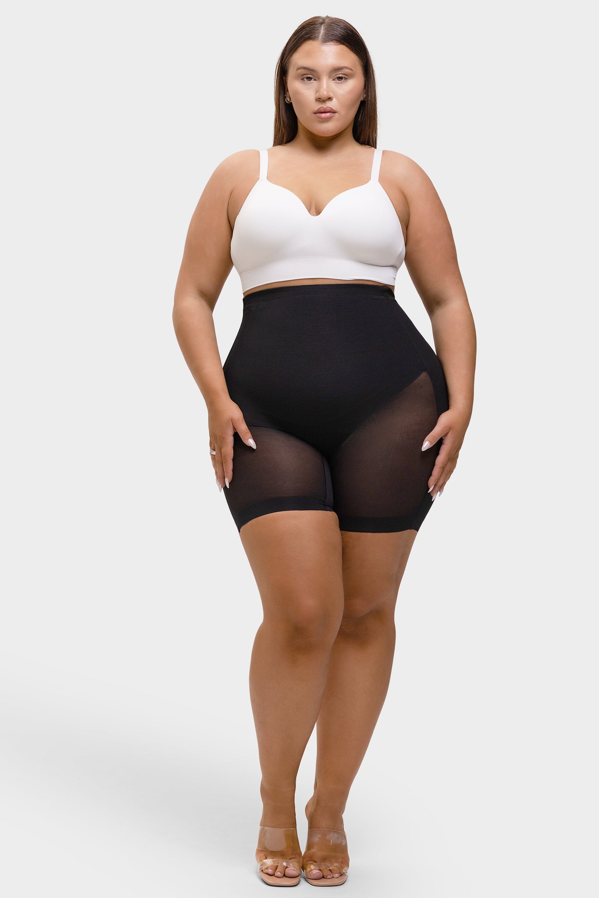 Woman wearing a white top and black sheer shorts on a white background