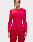 Person wearing a bright pink bodysuit on a light gray background