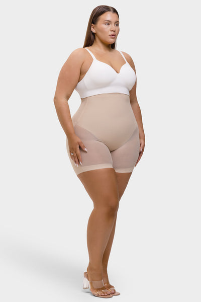 Woman wearing beige shapewear and a white top on a white background
