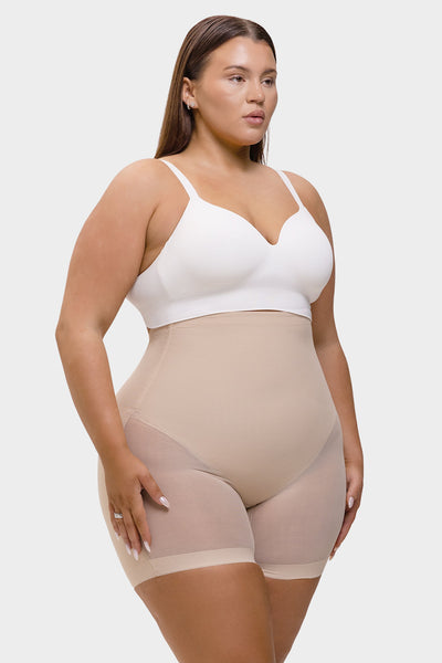 Woman wearing a white bra and beige shapewear on a plain background