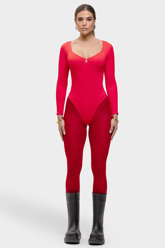 Woman wearing a red bodysuit with long sleeves and black boots on a white background