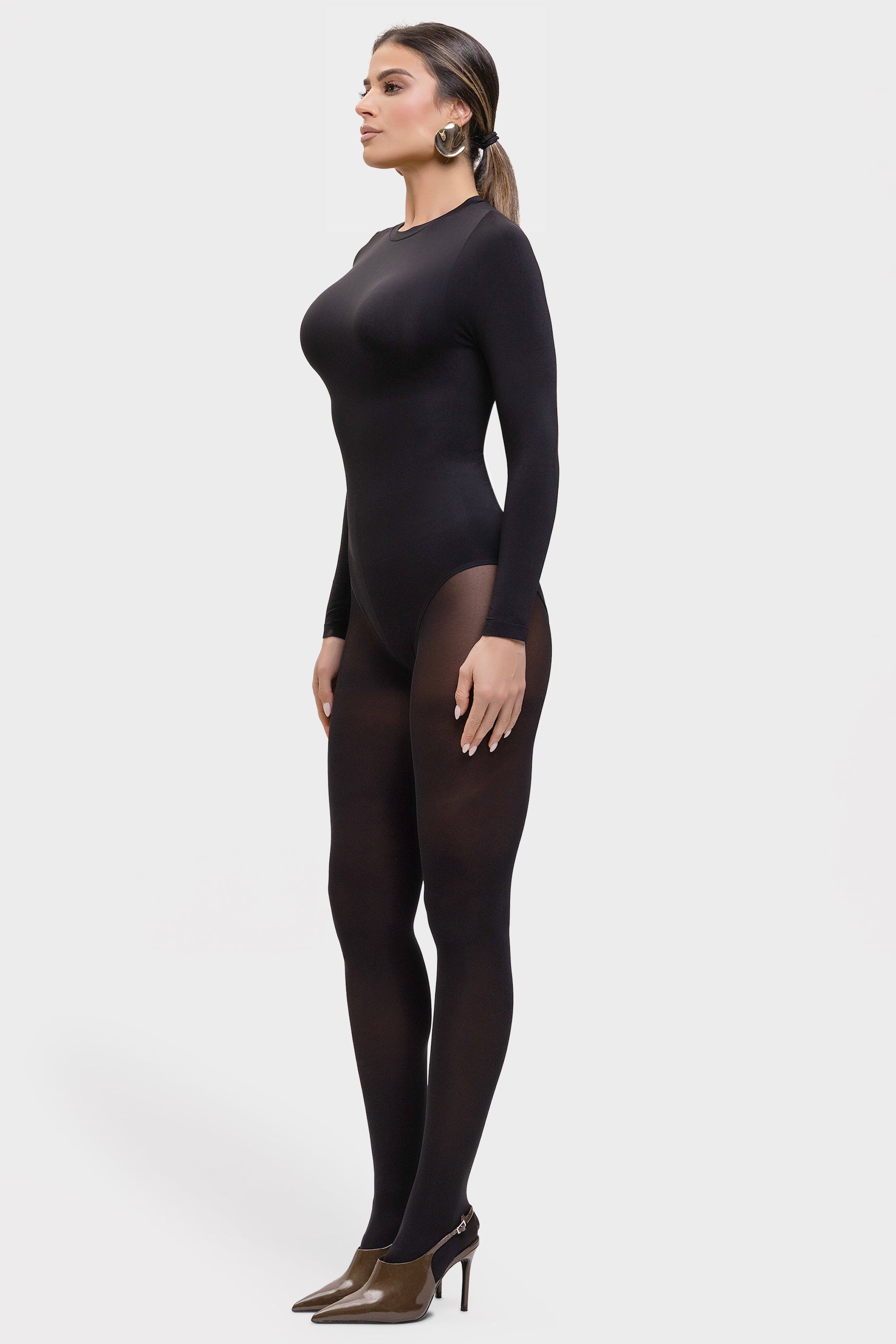 Woman wearing a black bodysuit and tights on a white background