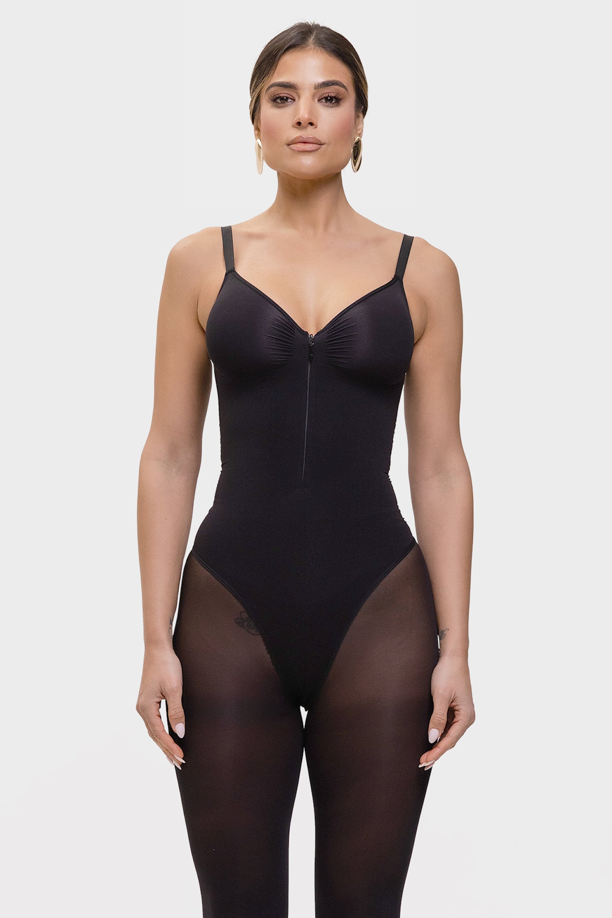 Woman wearing a black bodysuit on a white background