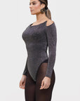 Woman wearing a sparkly black long-sleeve bodysuit on a light gray background