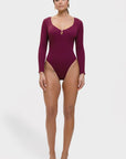 Woman wearing a maroon swimsuit with long sleeves on a white background