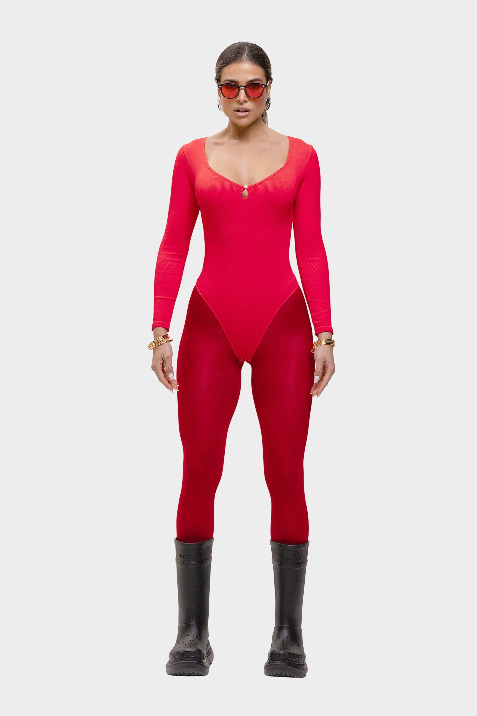 Person wearing a red bodysuit with black boots on a white background
