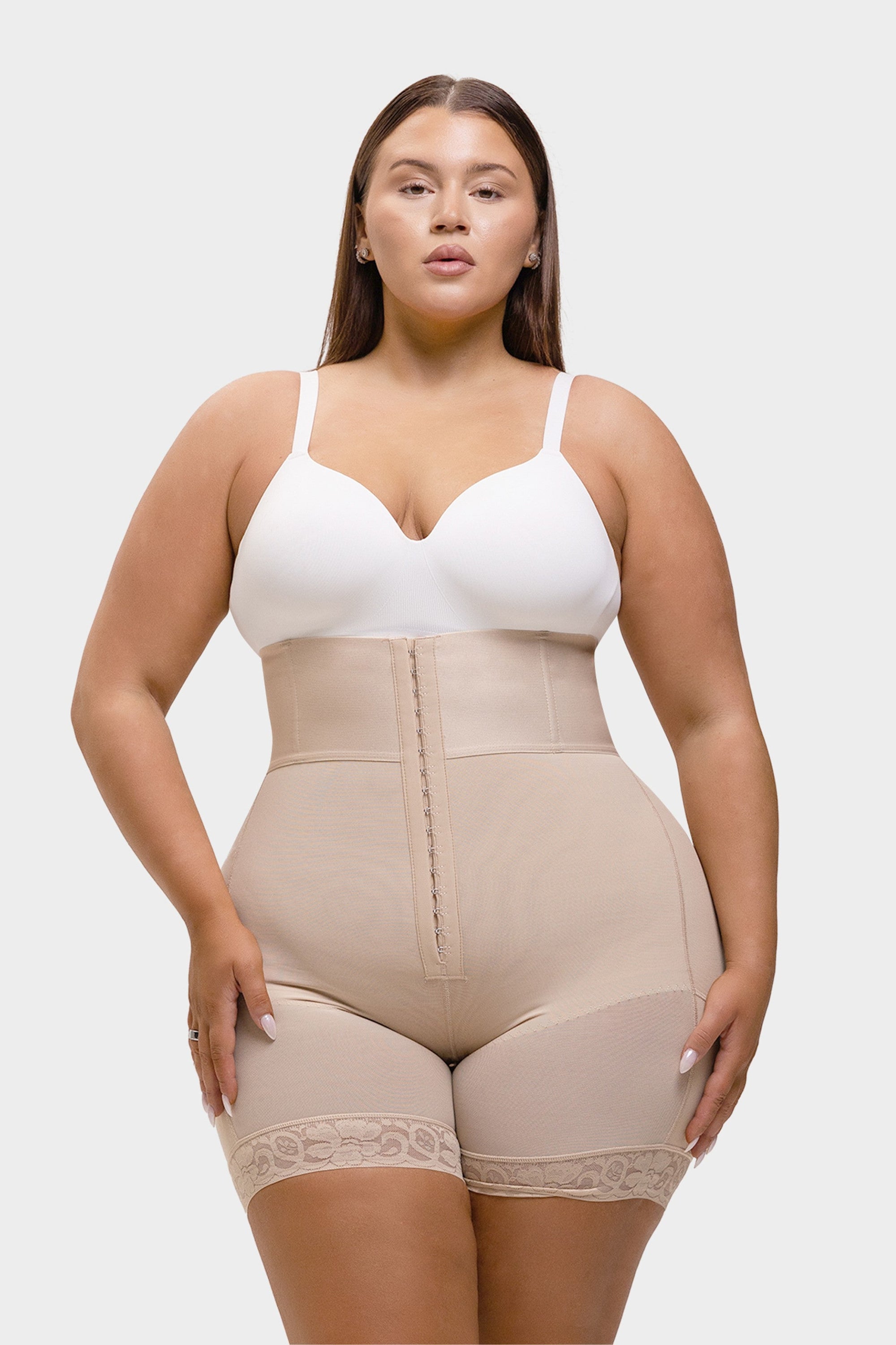 Woman wearing a white bra and beige shapewear on a white background