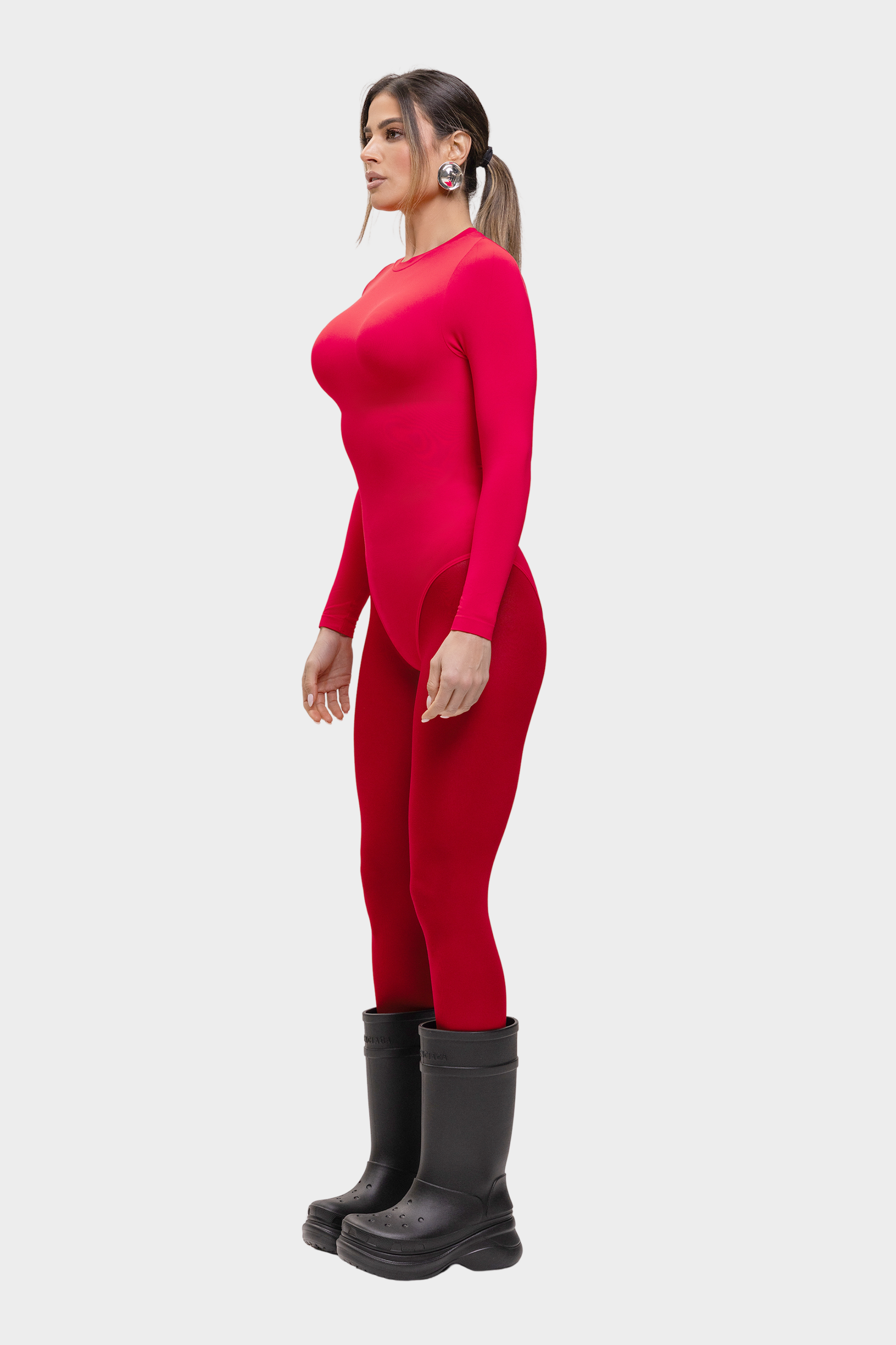 Woman wearing a red outfit with black boots on a white background