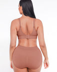 Woman wearing a brown sports bra and high-waisted leggings on a white background