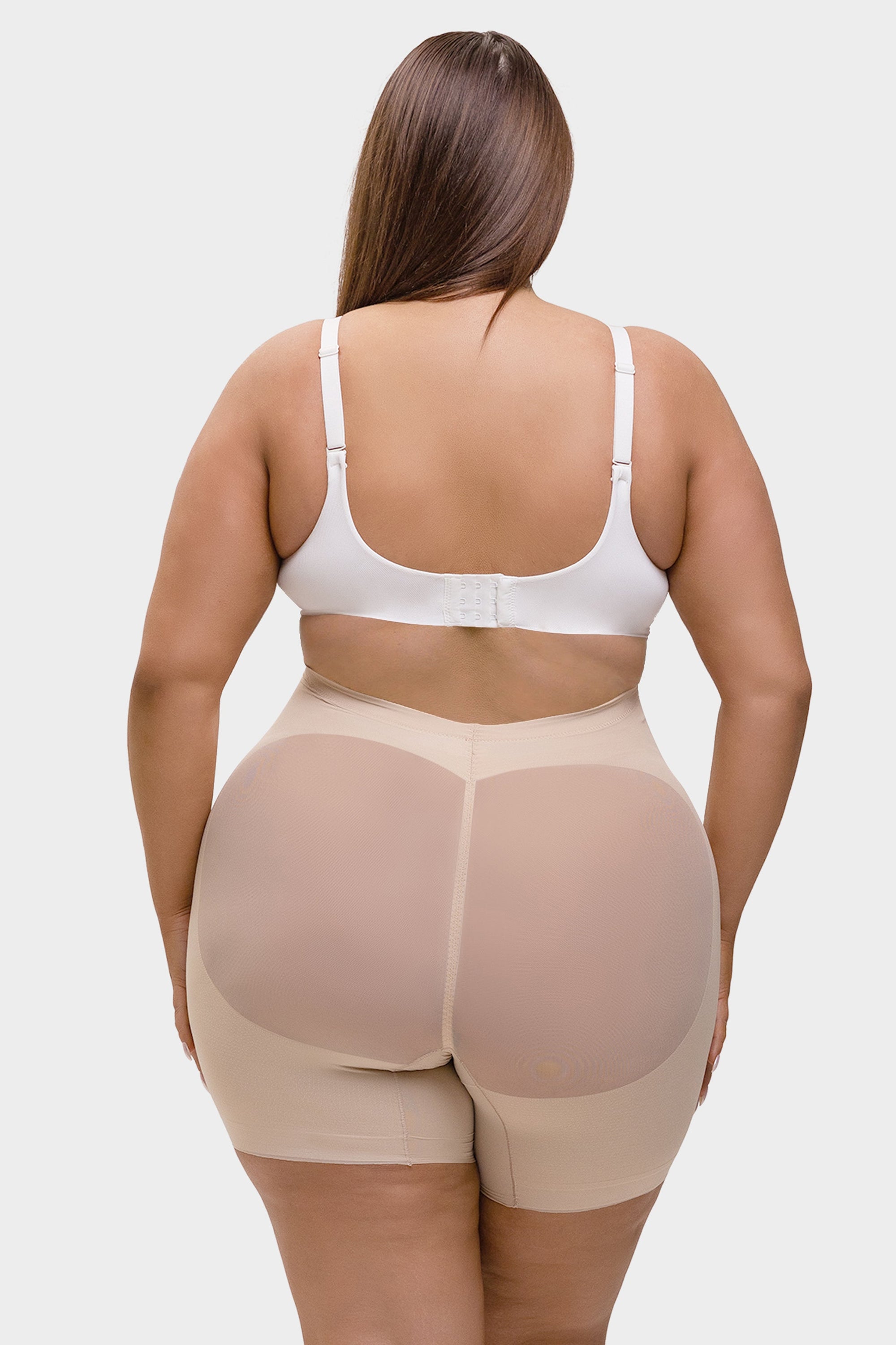 Person wearing a beige shapewear garment on a white background