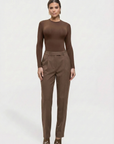 Woman wearing a brown long-sleeve top and pants on a white background