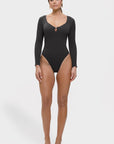 Woman wearing a black long-sleeve swimsuit on a white background