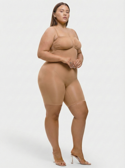 Person wearing a beige bodysuit on a white background