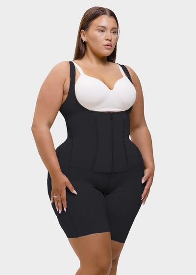 Woman wearing a black waist trainer over a white bralette on a plain background